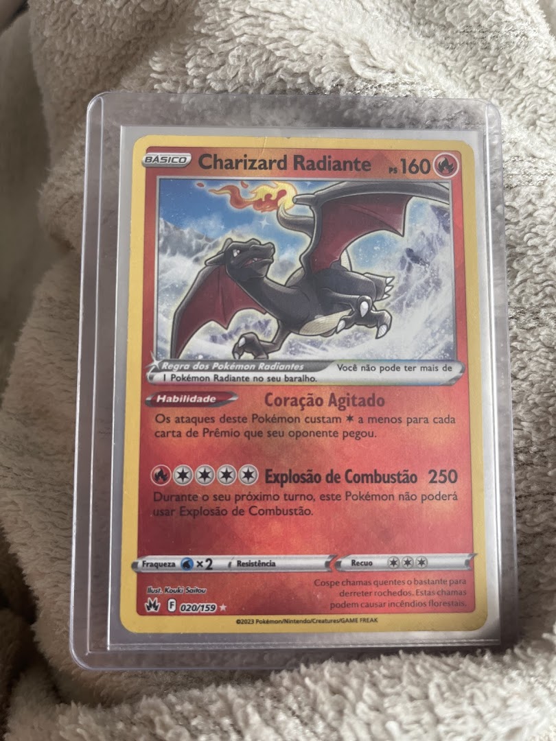 A close-up of a Charizard Radiant Pokémon trading card in Portuguese.