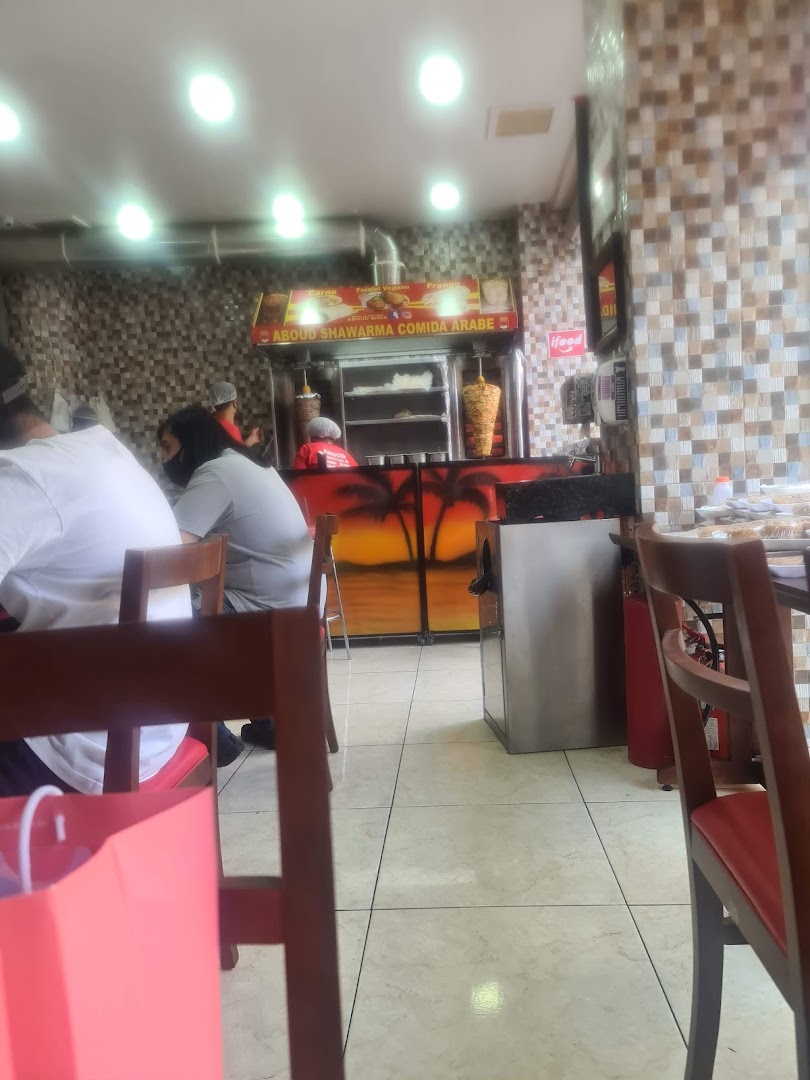 Interior view of a shawarma restaurant with customers and a shawarma spit.