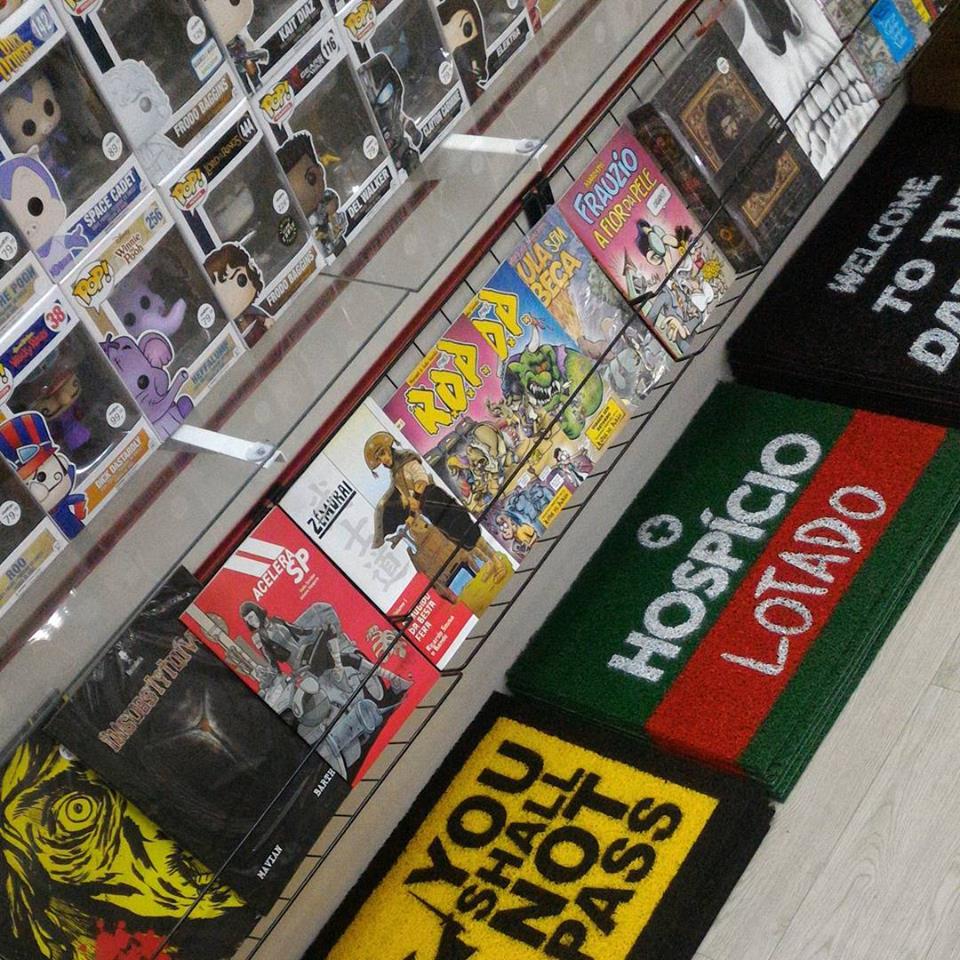 A display of pop culture merchandise, including Funko Pops and comic books, with novelty doormats.