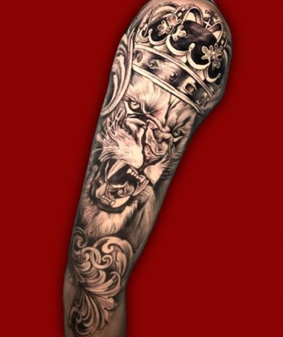 A detailed tattoo of a roaring lion wearing a crown on a person's arm.