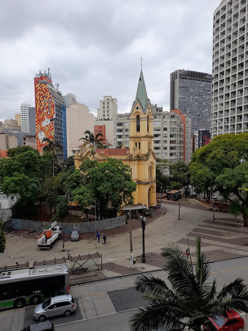 An aerial view of a city square with a yellow church and surrounding buildings.