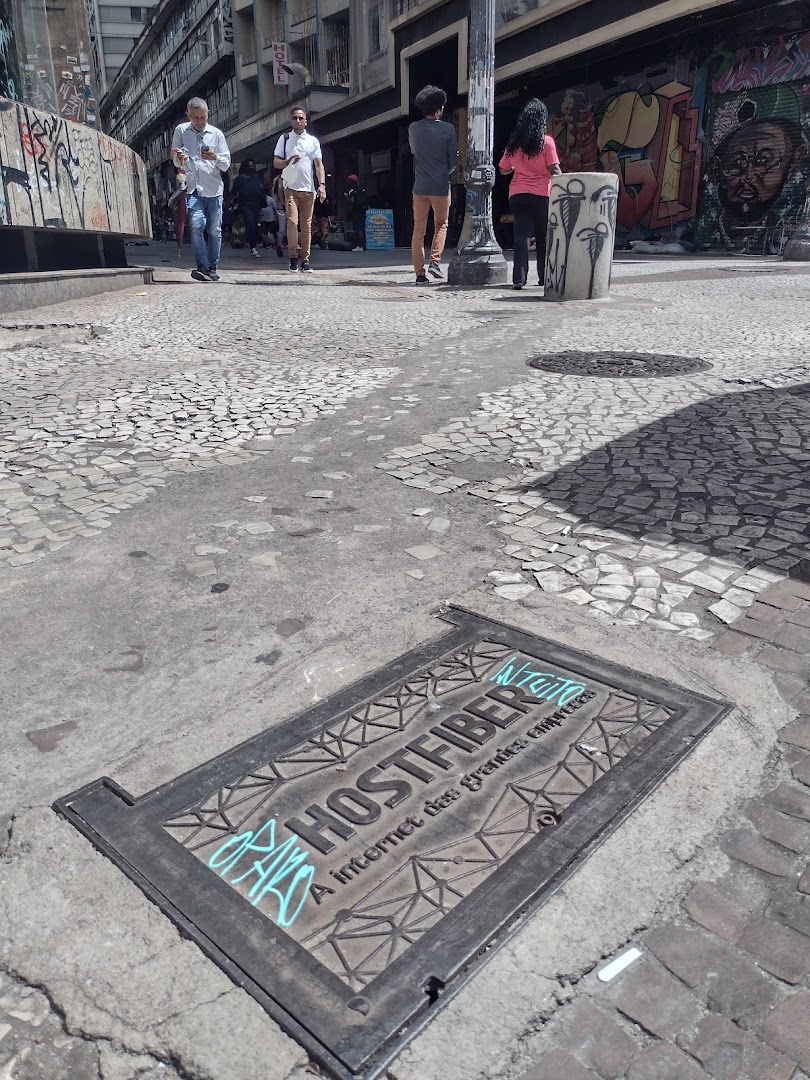 People walking on a street with graffiti and a manhole cover.