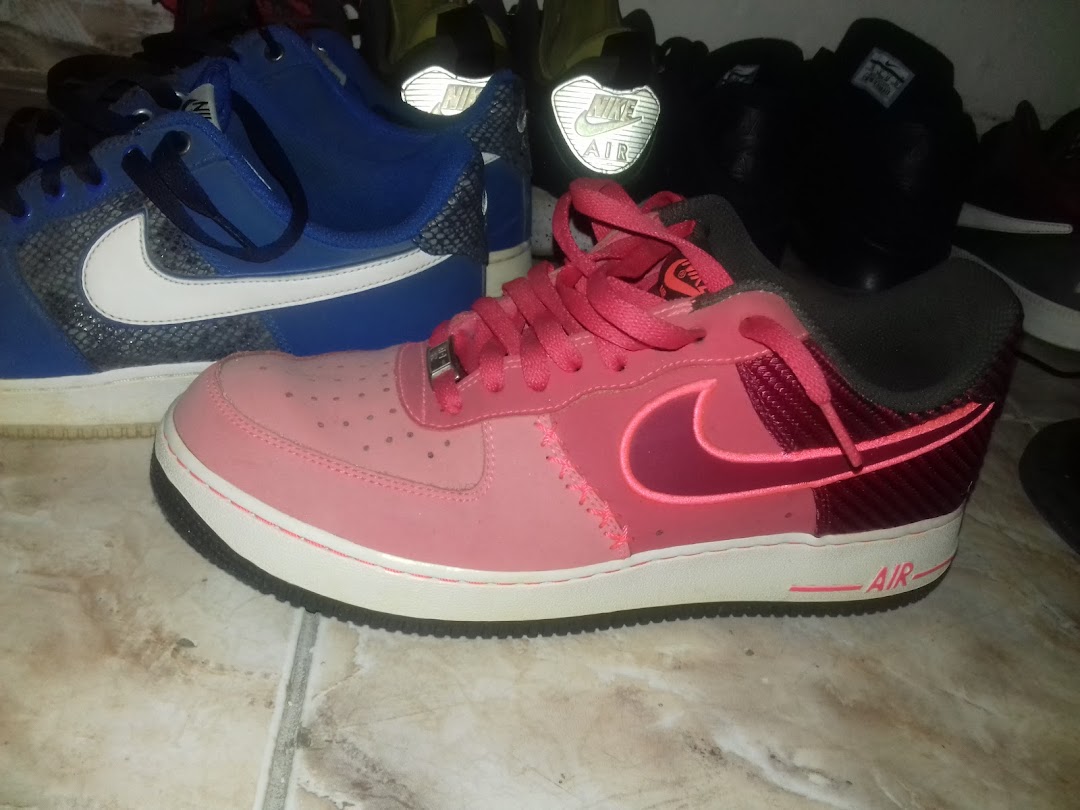 A close-up shot of several pairs of Nike sneakers, with a pink pair in the foreground.