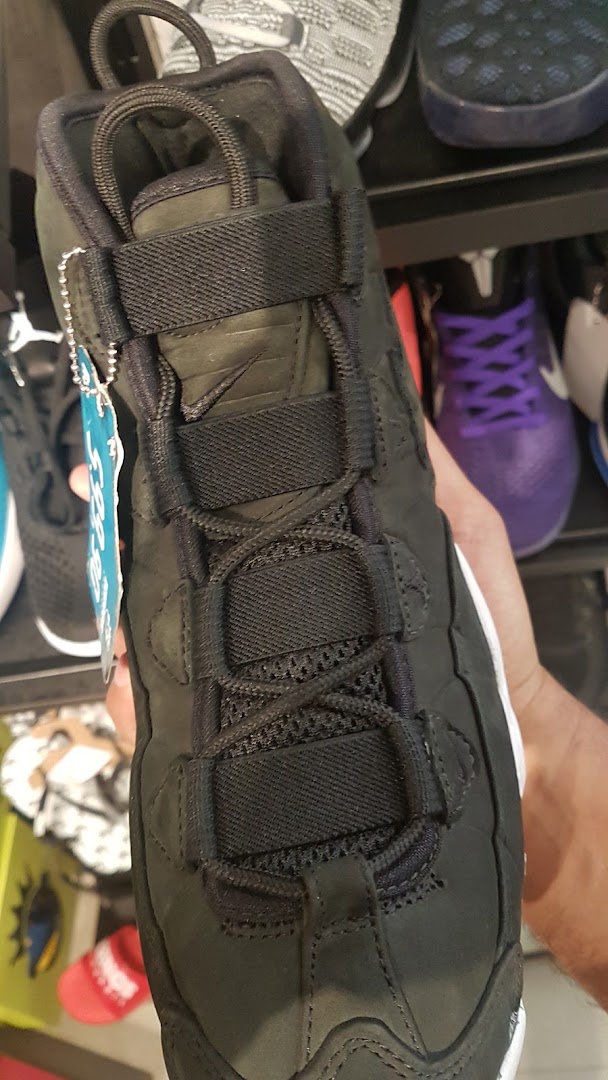 A close-up view of a black sneaker with intricate lacing and a tag.