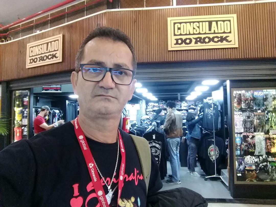 A man stands in front of a store selling rock-themed merchandise, including t-shirts and posters.