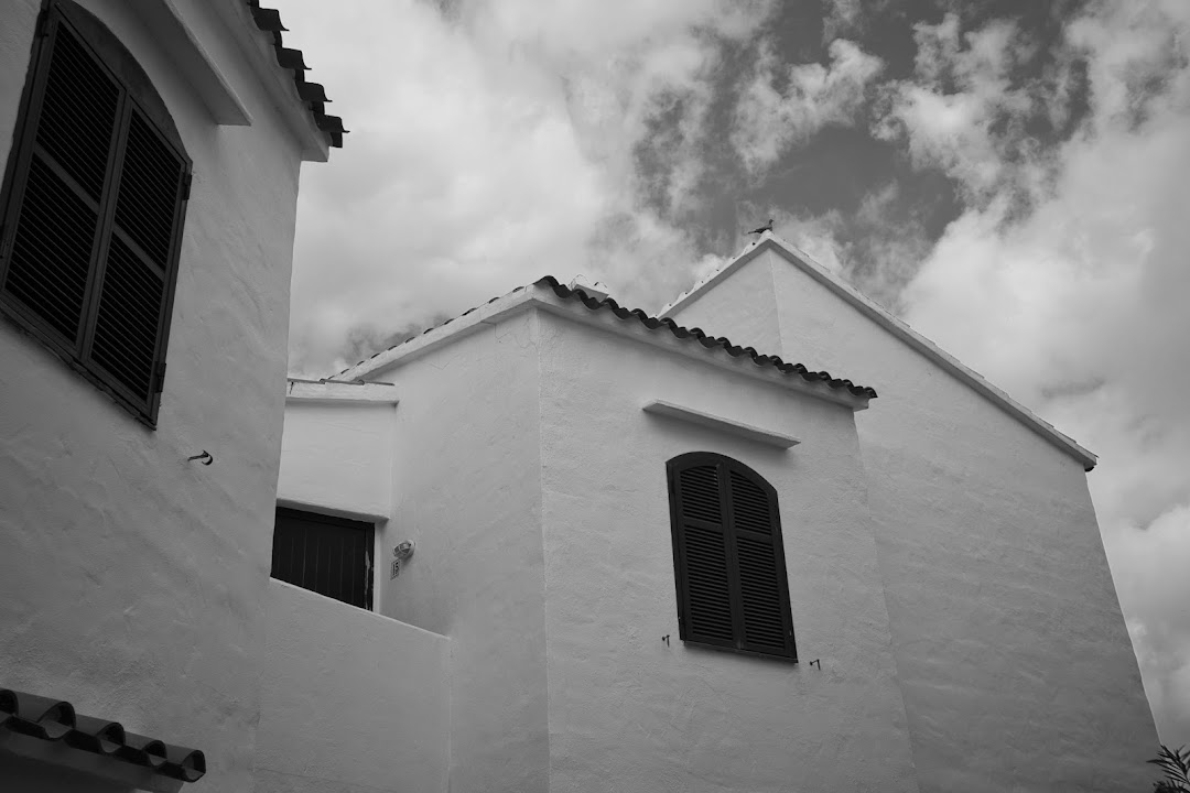 A black and white image of white buildings with dark shutters and tiled roofs.