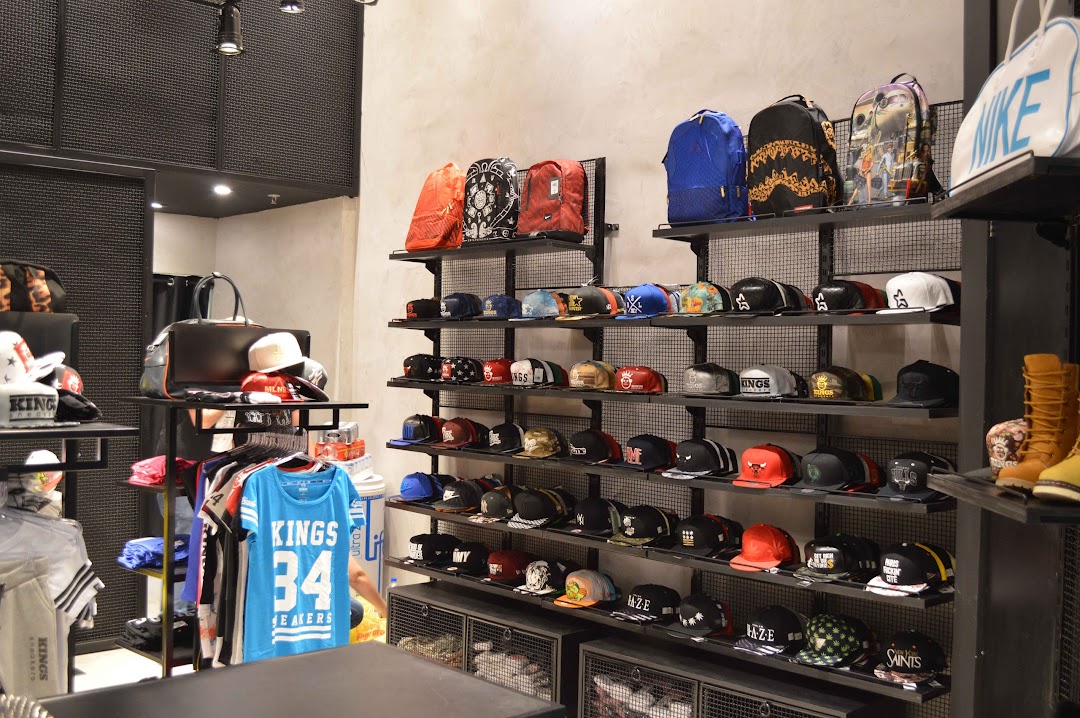 Interior view of a sneaker and apparel store showcasing shelves filled with hats, backpacks, and clothing.