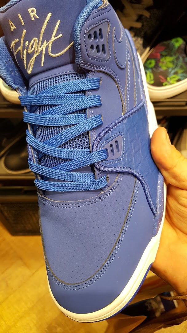 Close-up of a blue Nike Air Flight sneaker being held by a hand.