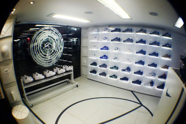 Interior of a sneaker shop showcasing a wide variety of Nike shoes on illuminated shelves.