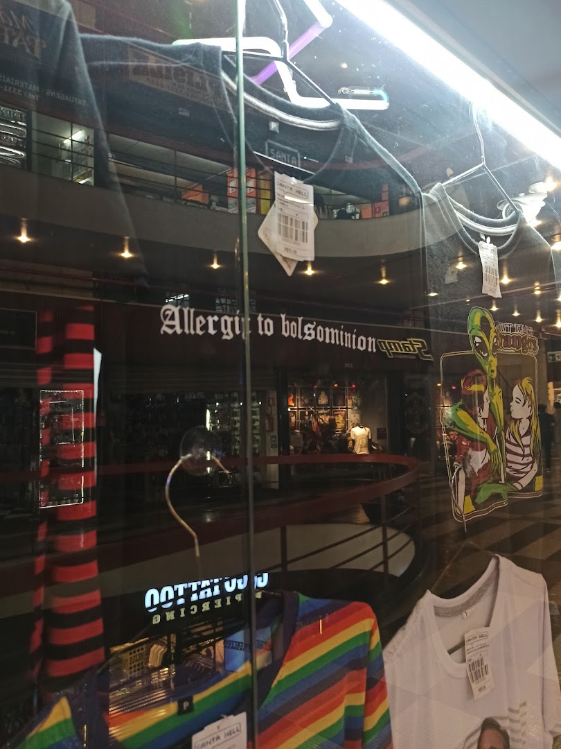 A shop window displaying clothing with colorful designs and a sign that says 'Allergy to bolsominion'.