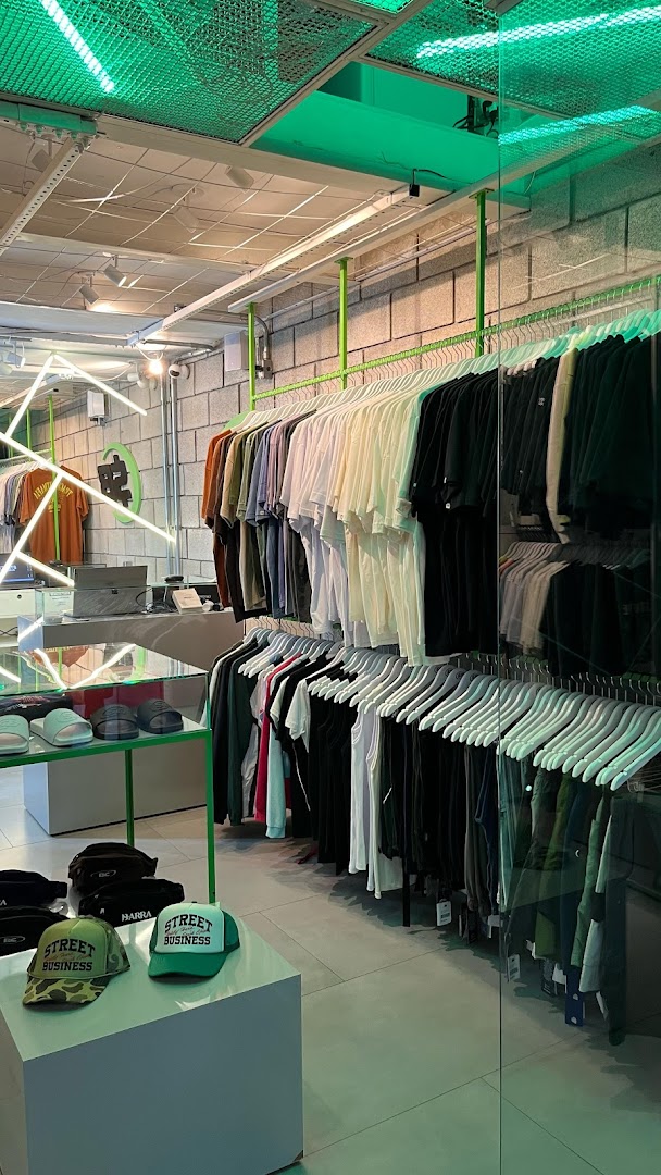 Interior of a modern clothing store with racks of t-shirts and caps.