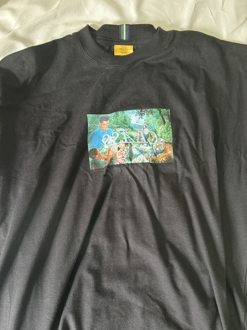 A black t-shirt with a colorful graphic print featuring people and a tiger in a natural setting.