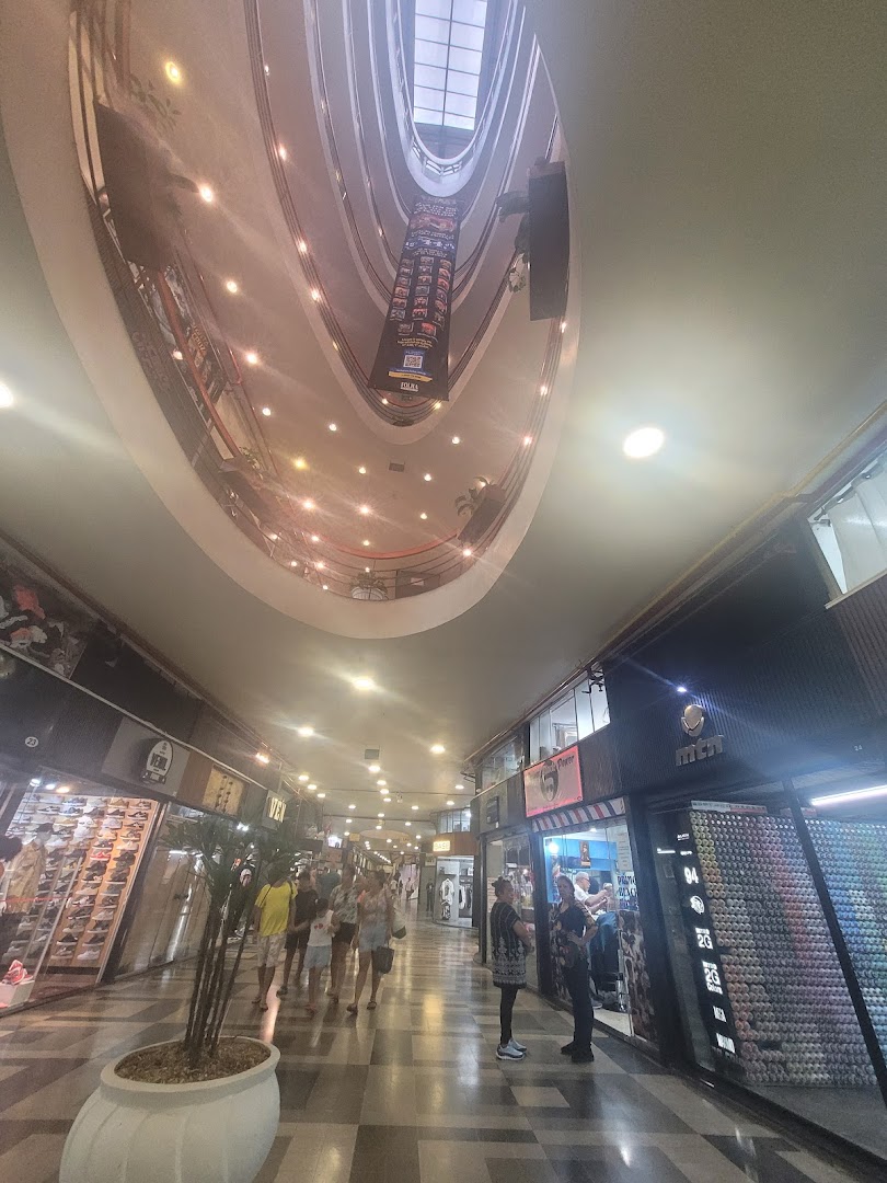 A view of a shopping mall interior with multiple shops and people walking.