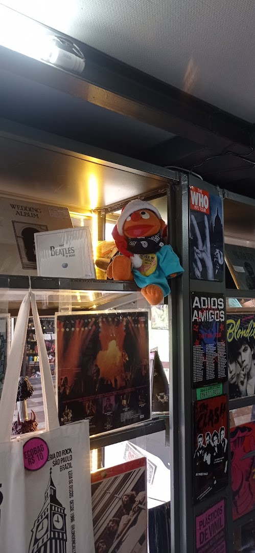 A display shelf in a record store featuring vinyl albums, band posters, and a Muppet character.
