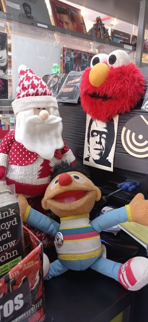 Plush toys of Santa Claus, Elmo, and Ernie are displayed among records and posters.