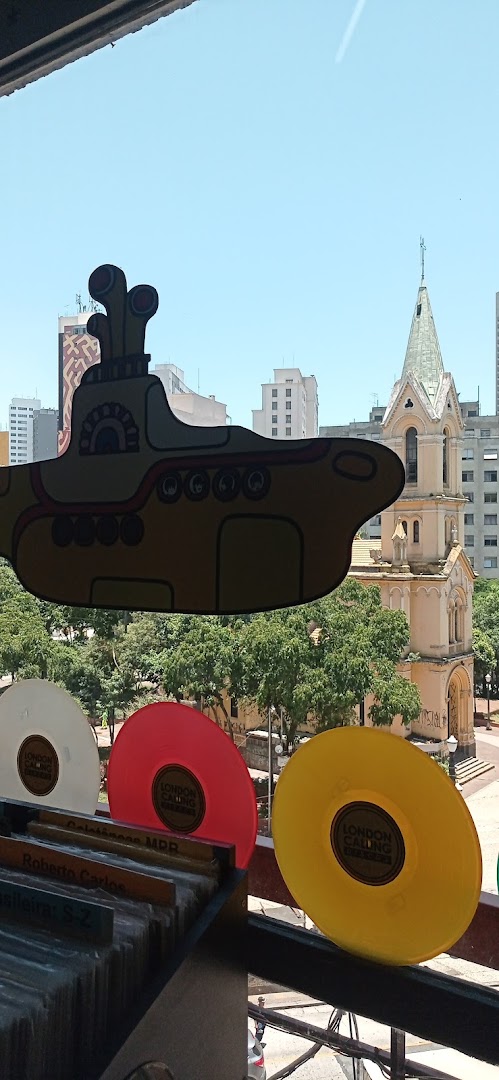 Colorful vinyl records and a Yellow Submarine cutout displayed with a cityscape and church in the background.