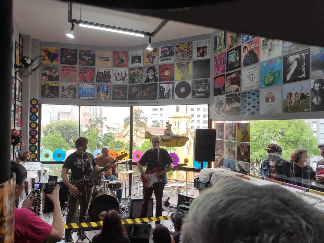 A band performs live in a record store filled with album art displayed on the walls.