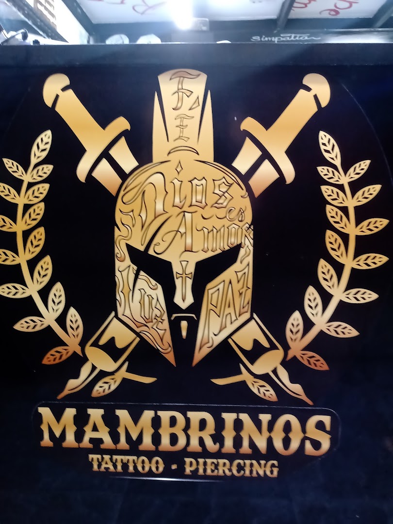 A gold and black logo for Mambrinos Tattoo & Piercing featuring a Spartan helmet and swords.