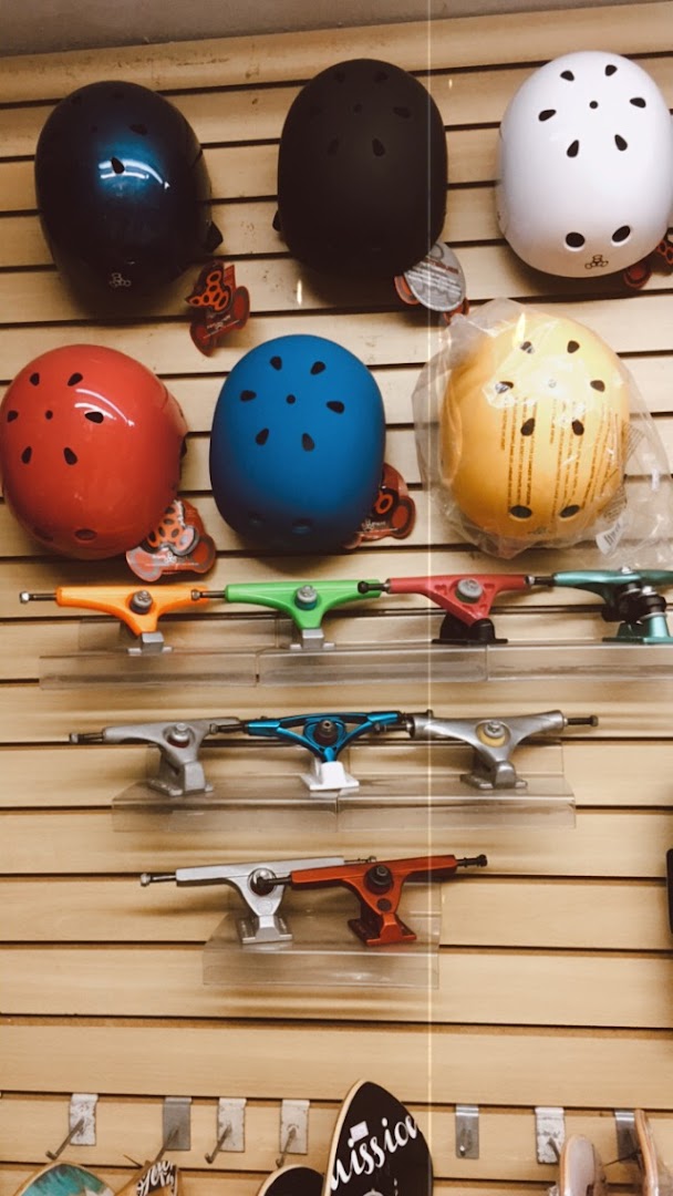 Skate shop interior displaying colorful helmets and skateboard trucks on a slatted wall.