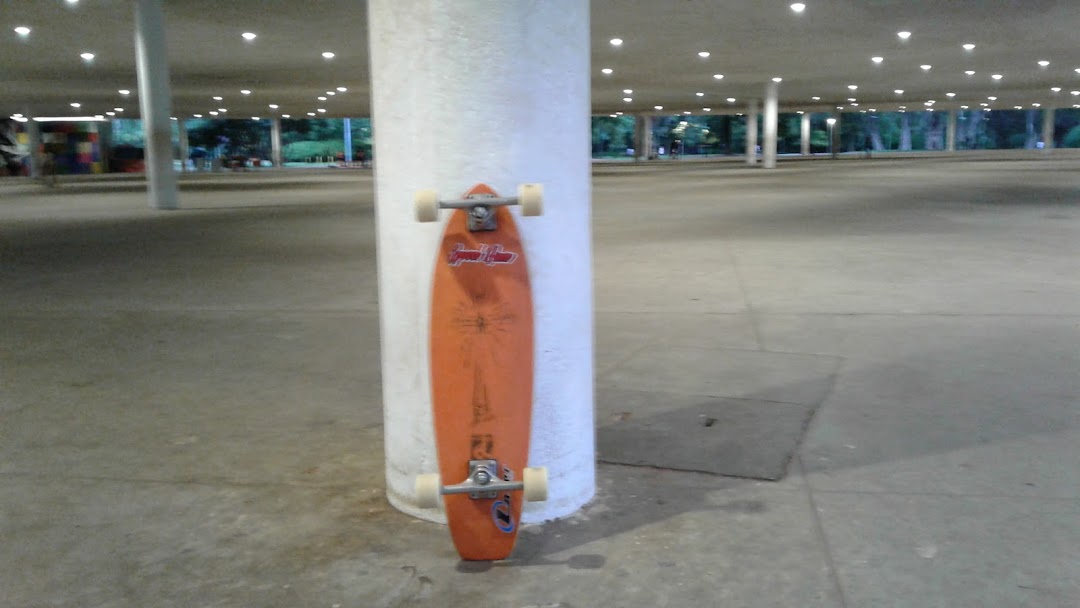 An orange skateboard leans against a white pillar in an open, covered area.