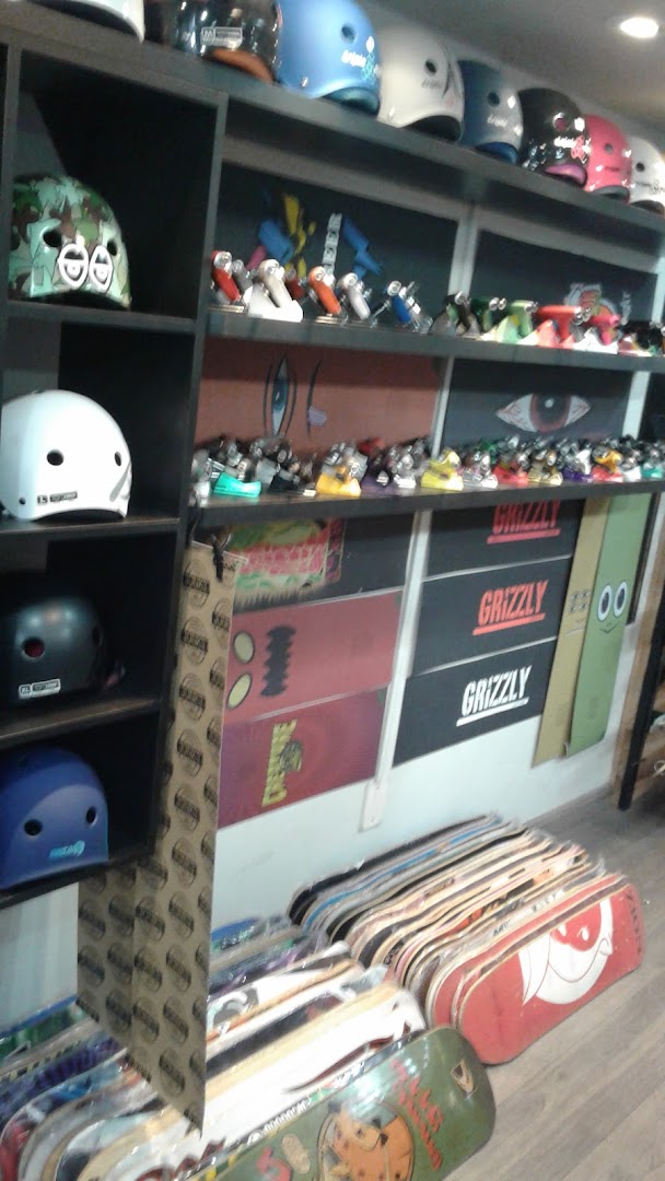 A skate shop interior displaying helmets, skateboards, and accessories on shelves and the floor.