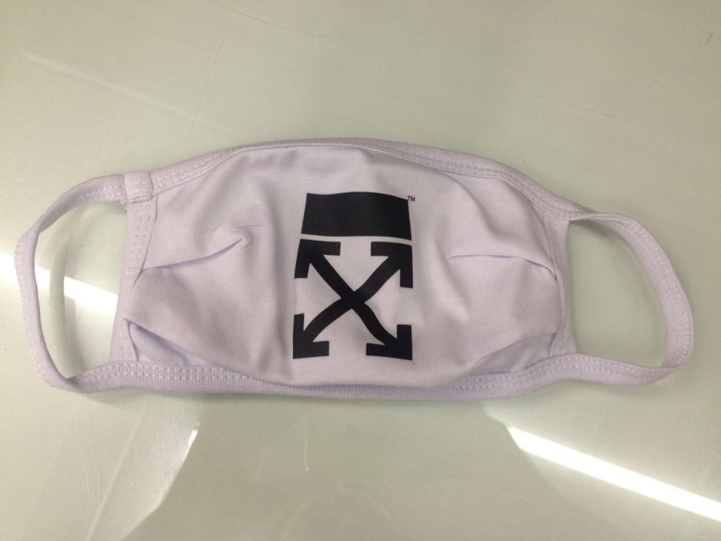 A white face mask with a black Off-White logo is displayed on a white surface.
