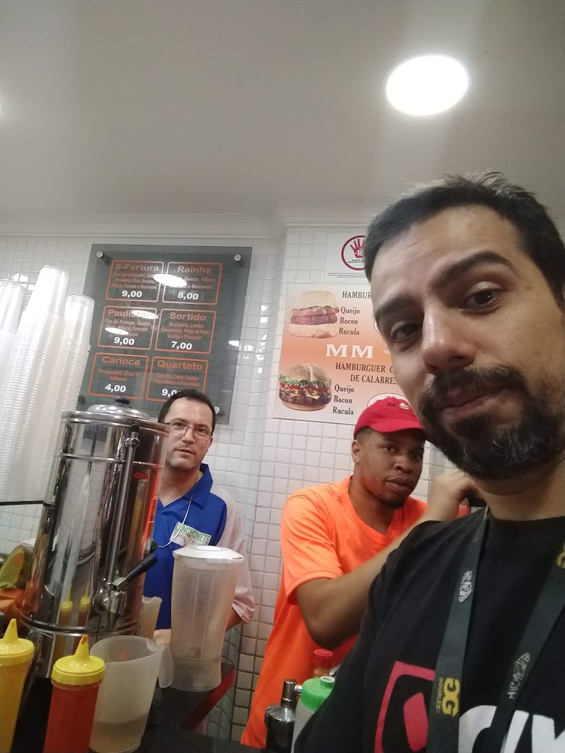 Three men are in front of a counter with a menu and food items.