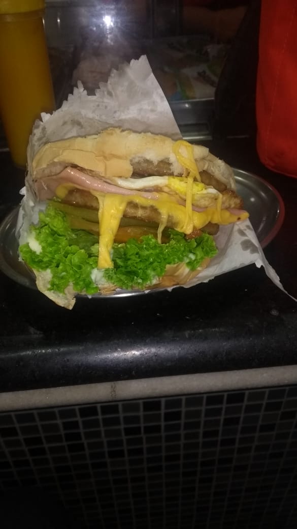 A delicious, loaded sandwich with lettuce, cheese, ham, egg, and pickles on a long bun.