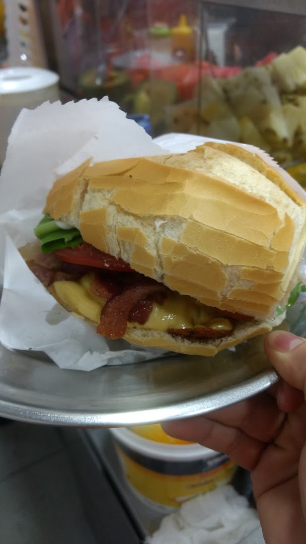 A close-up shot of a delicious sandwich with bacon, cheese, tomato, and lettuce on a bun.