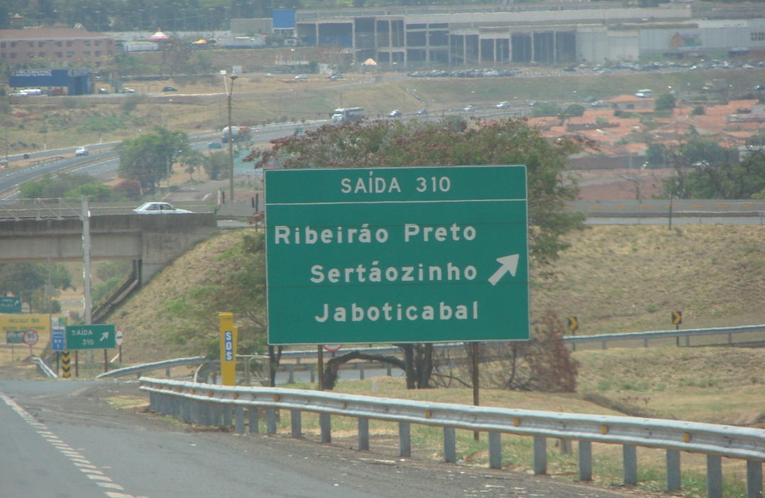 A green road sign indicating directions to Ribeirão Preto, Sertãozinho, and Jaboticabal.