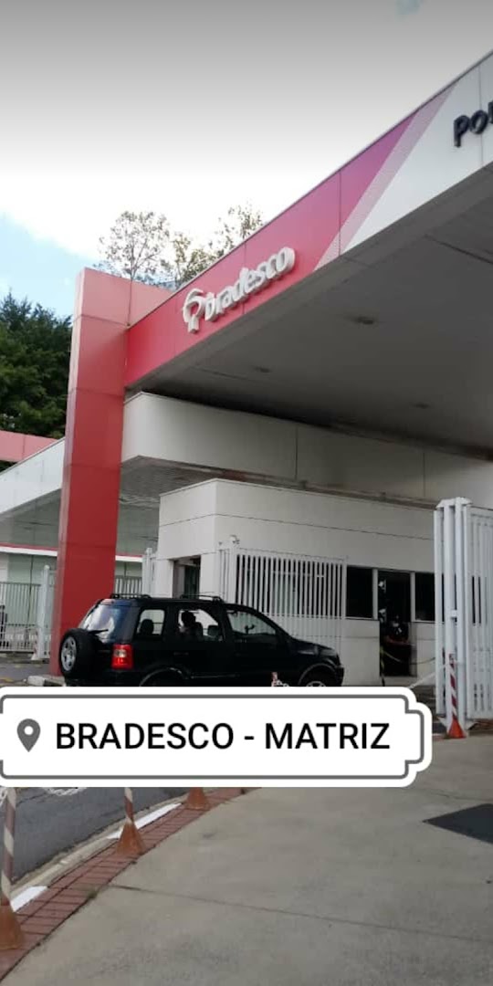 Exterior view of a Bradesco bank branch with a car parked in front.