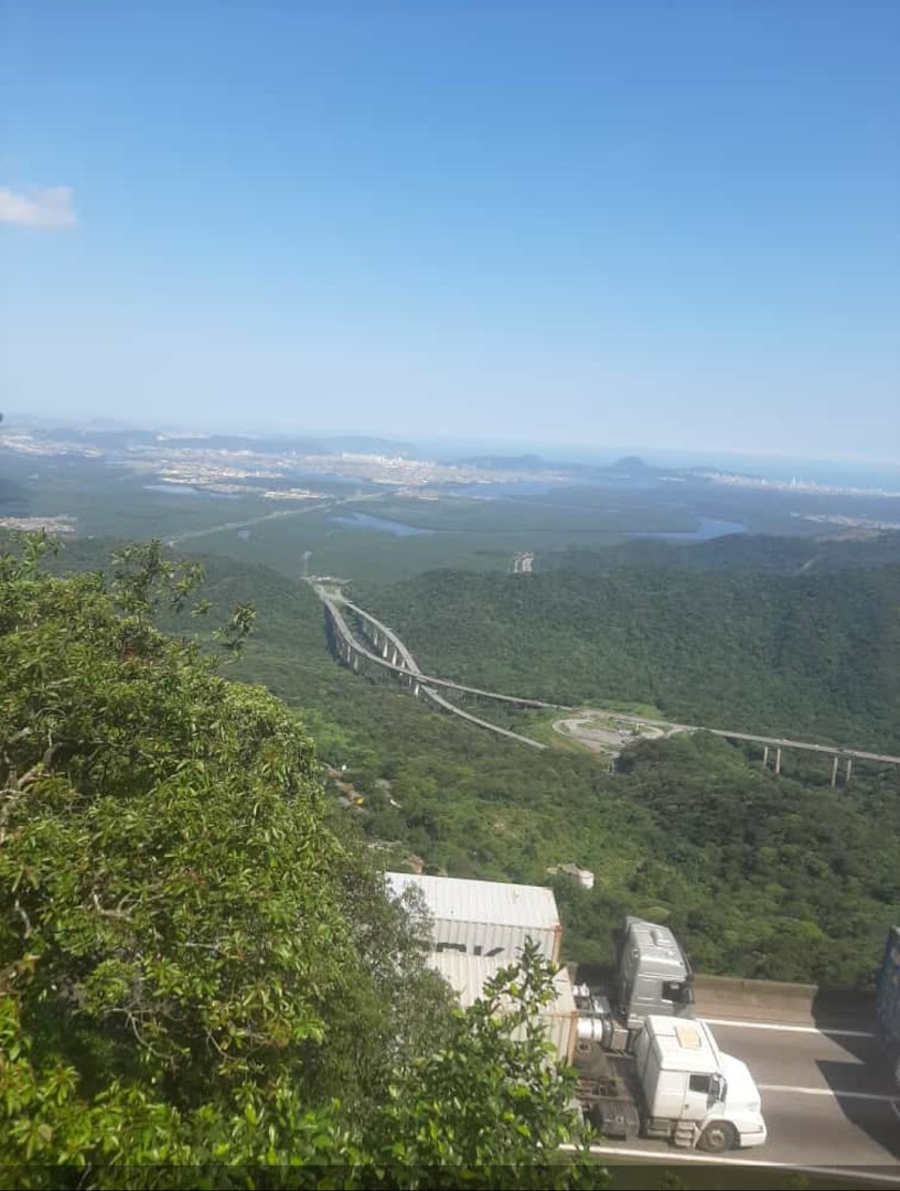 Scenic view of a highway with trucks, a city skyline, and a bridge in the distance.