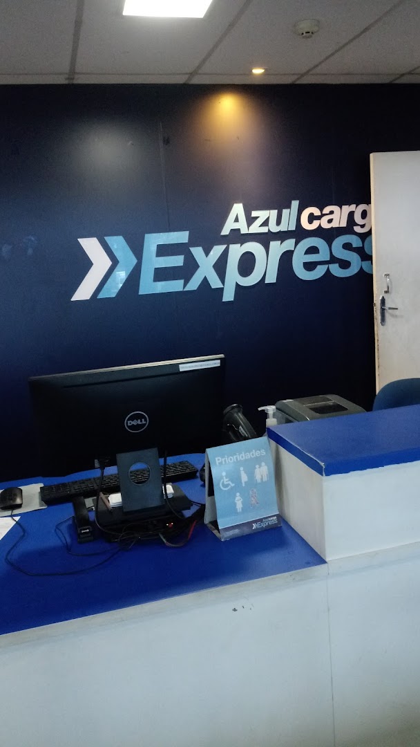 A counter with a computer, scanner, and signage for Azul Cargo Express.