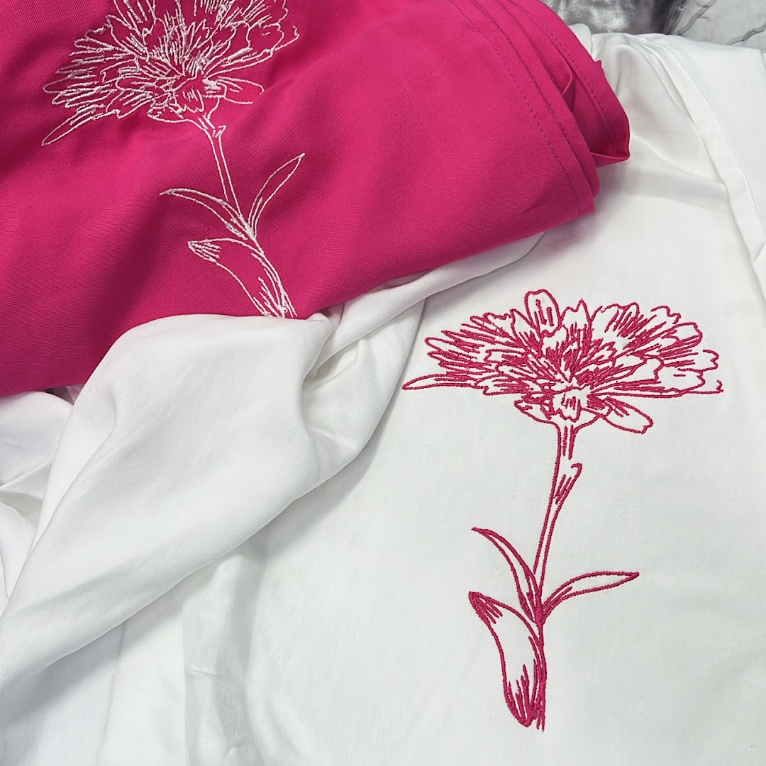 Close-up of embroidered flowers on pink and white fabric.
