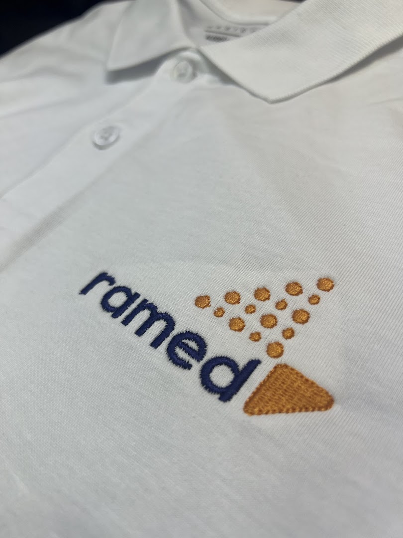 Close-up of a white polo shirt with embroidered logo and text.