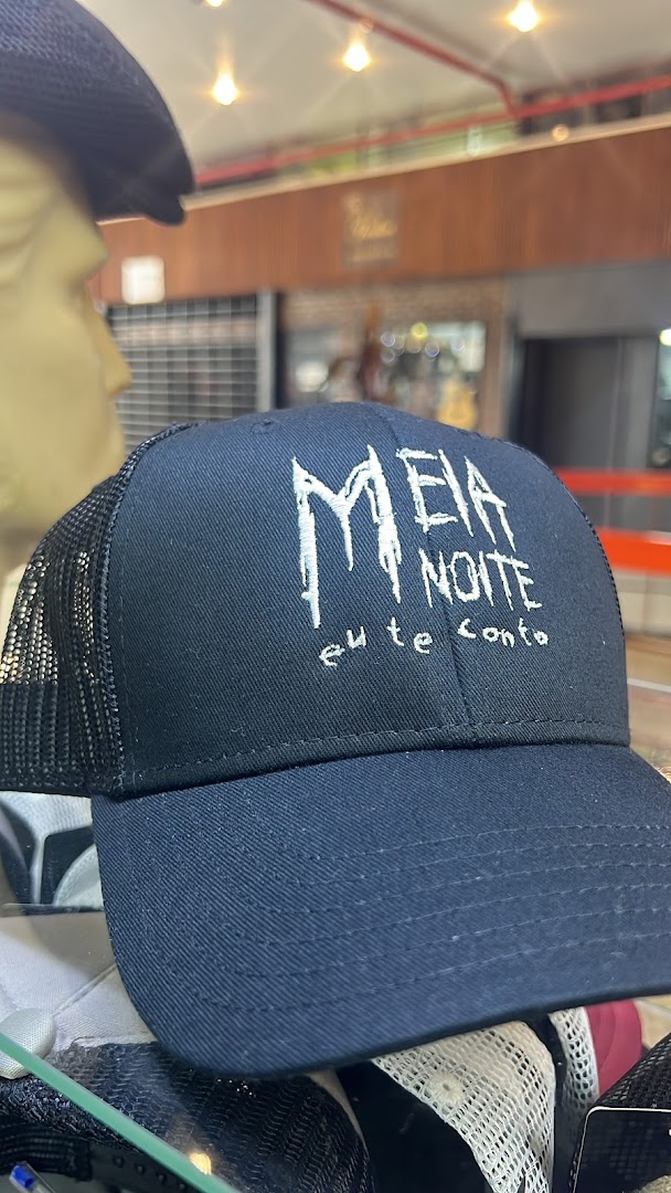 A close-up of a black trucker hat with white embroidered text on the front.