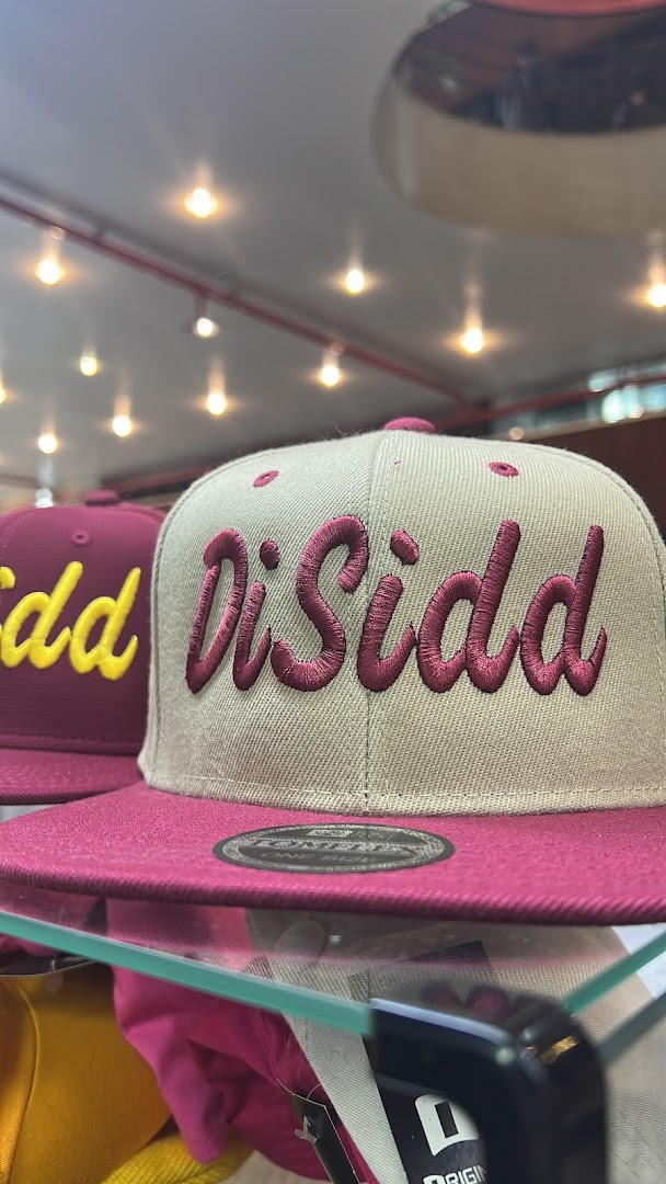 Close-up of two embroidered baseball caps, one with 'DiSidd' and another with yellow lettering.