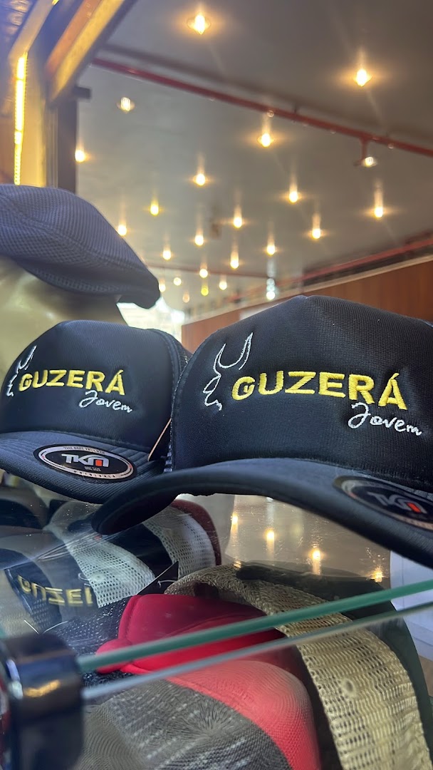 Close-up of embroidered trucker hats with the brand name 'GUZERÁ Jovem'.