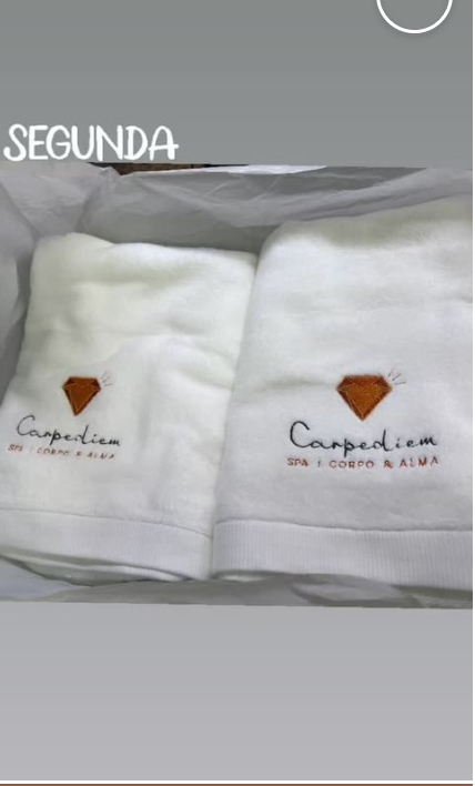 Two white fluffy towels with embroidered logos and text.
