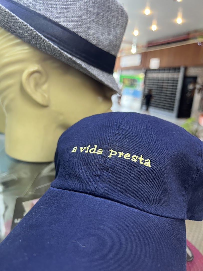 A close-up of a navy blue baseball cap with embroidered text, next to a mannequin wearing a fedora.