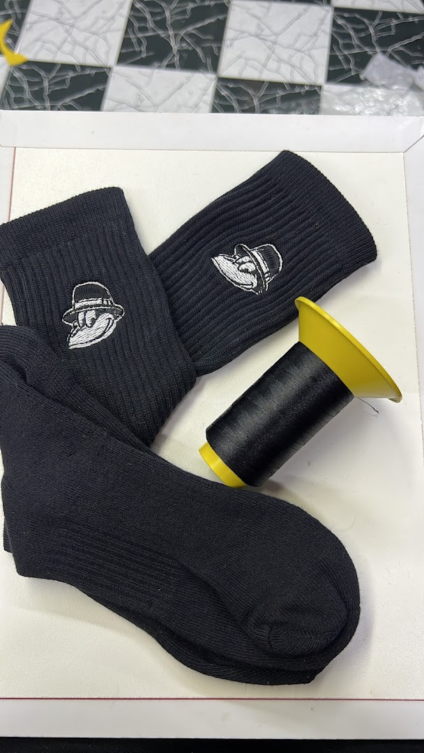 Black socks with embroidered cartoon characters and a spool of black thread.