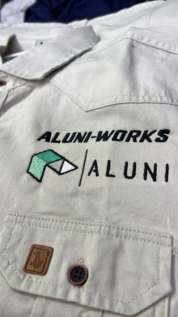 Close-up of a light-colored shirt with embroidered logos and a leather patch.