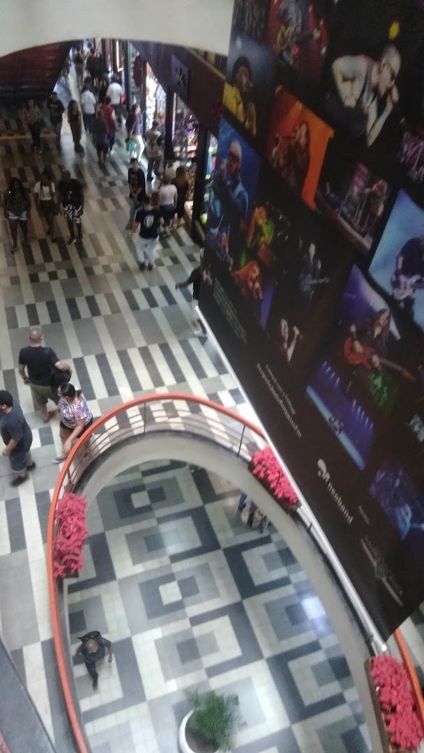 People walking in a mall with a large poster featuring rock musicians.