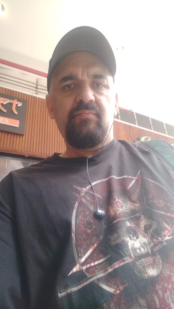 A man wearing a black t-shirt with a skull graphic and a baseball cap.