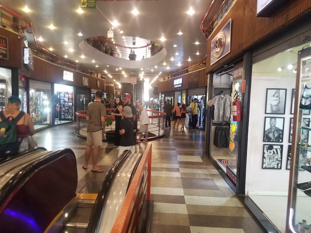 A view of a shopping mall interior with several shops and people walking around.