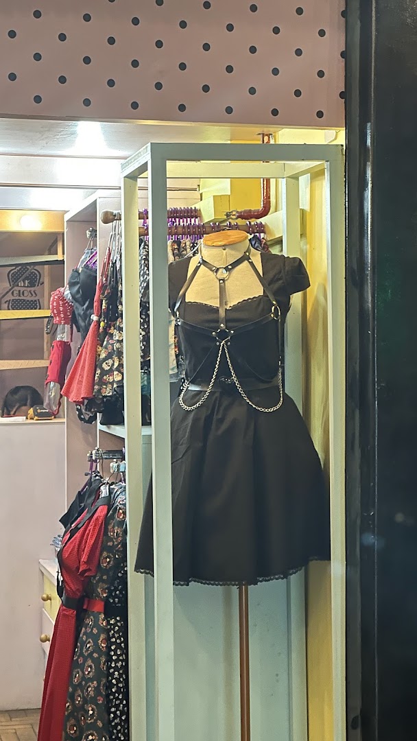 A mannequin displays a black dress with a harness and chains in a shop window.