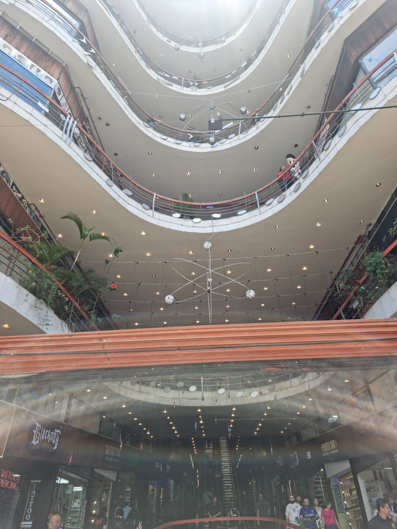 Interior view of a multi-level shopping mall with shops and escalators visible.