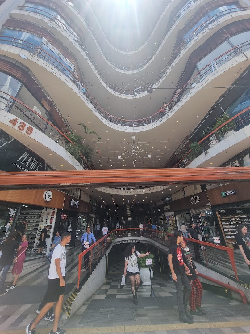People walking down stairs in a multi-level shopping arcade with various shops visible.