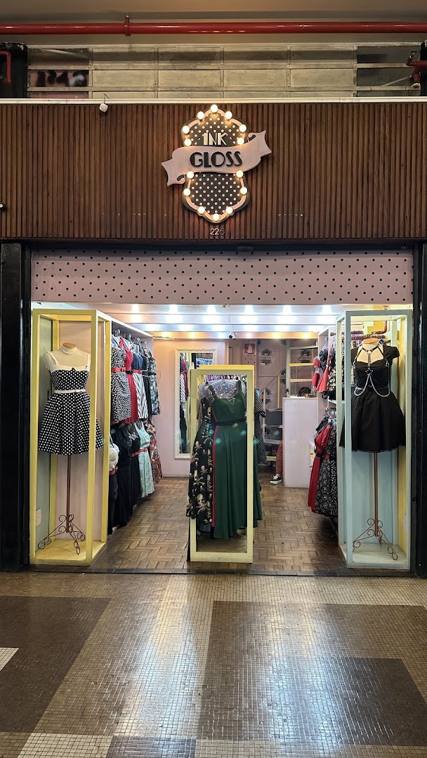 The entrance of a vintage-inspired clothing store with mannequins displaying dresses and racks of apparel.