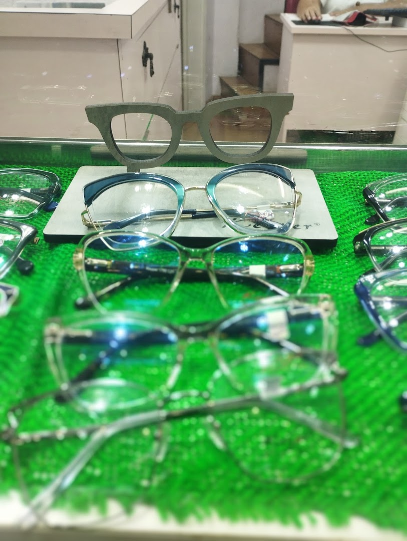 A display of various stylish eyeglasses on a bright green surface.